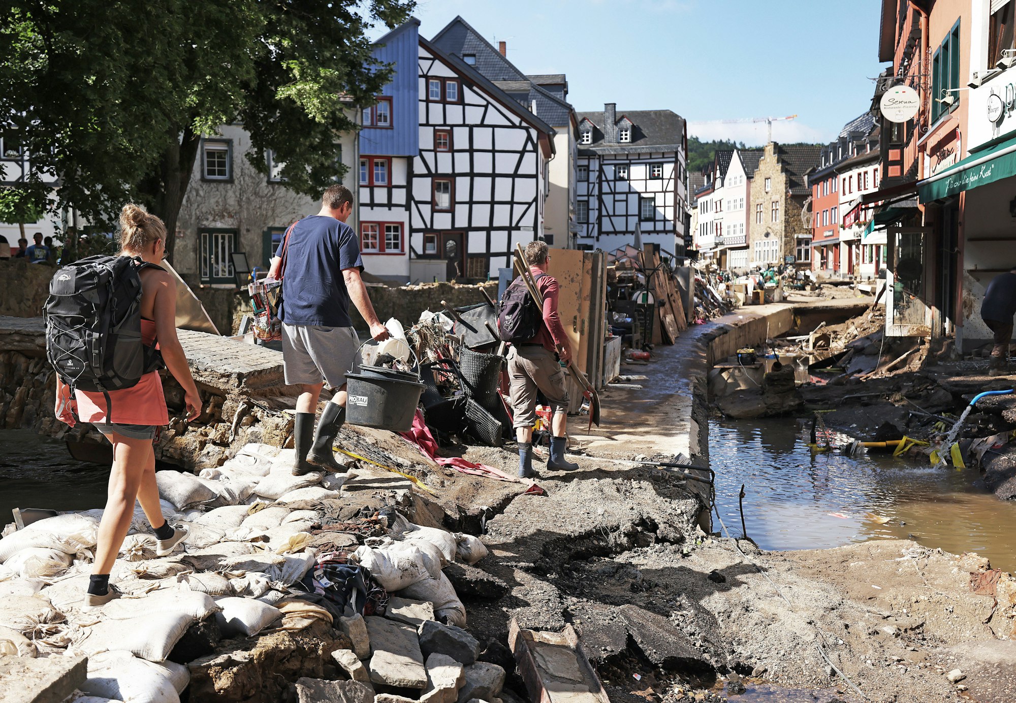 Helfer gehen durch den Ortskern. In Bad Münstereifel hat die über die Ufer getretene Erft erhebliche Schäden angerichtet.