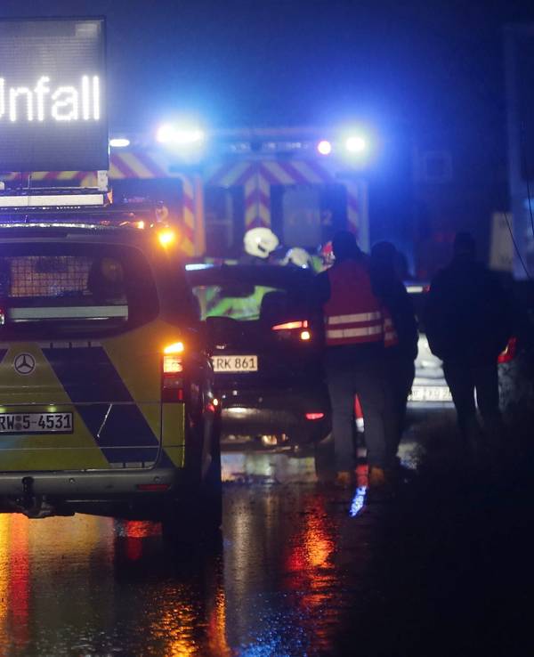 Polizei- und Feuerwehrfahrzeuge mit Blaulicht sichern eine Unfallstelle auf der Autobahn.