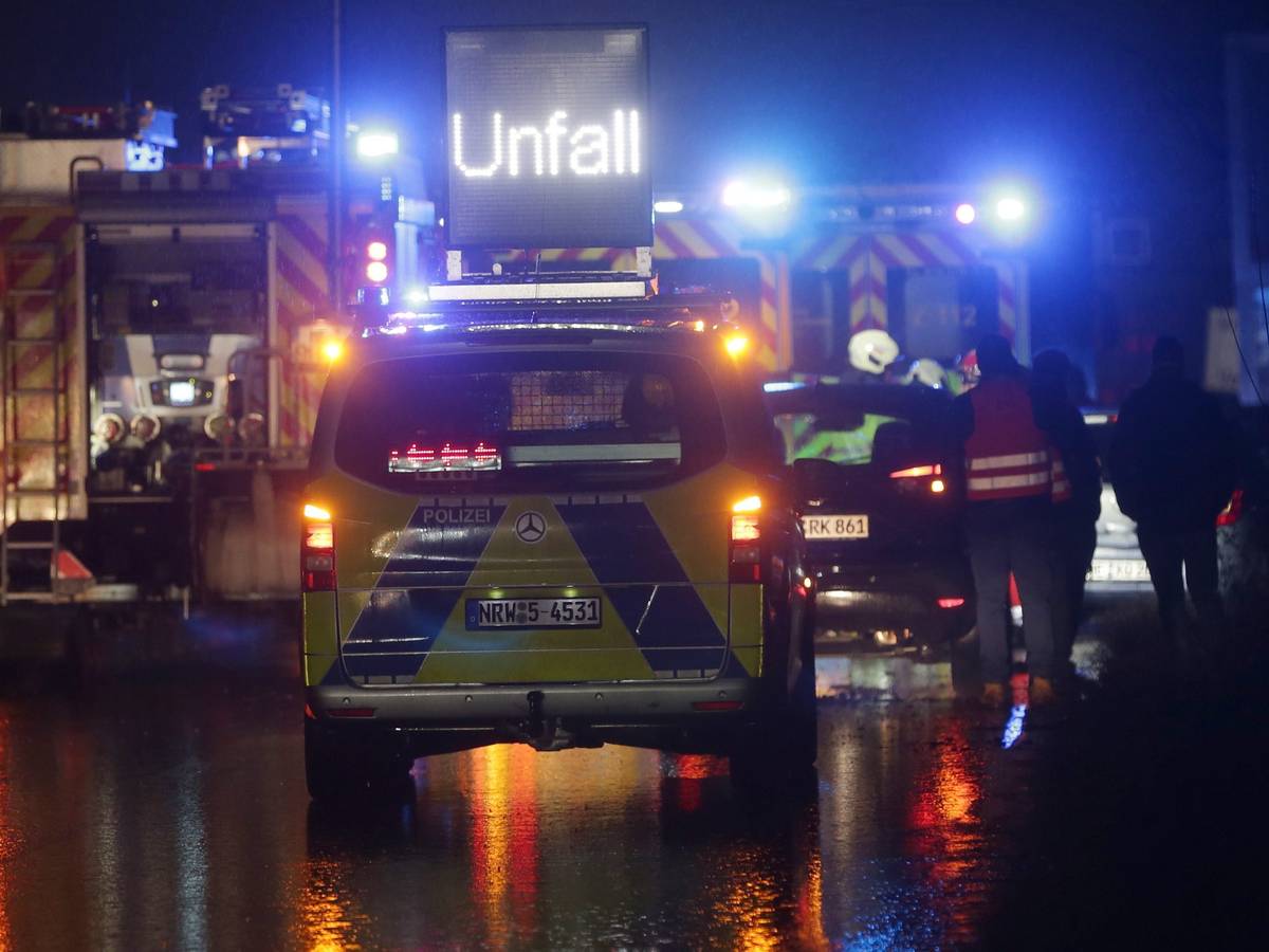 Polizei- und Feuerwehrfahrzeuge mit Blaulicht sichern eine Unfallstelle auf der Autobahn.