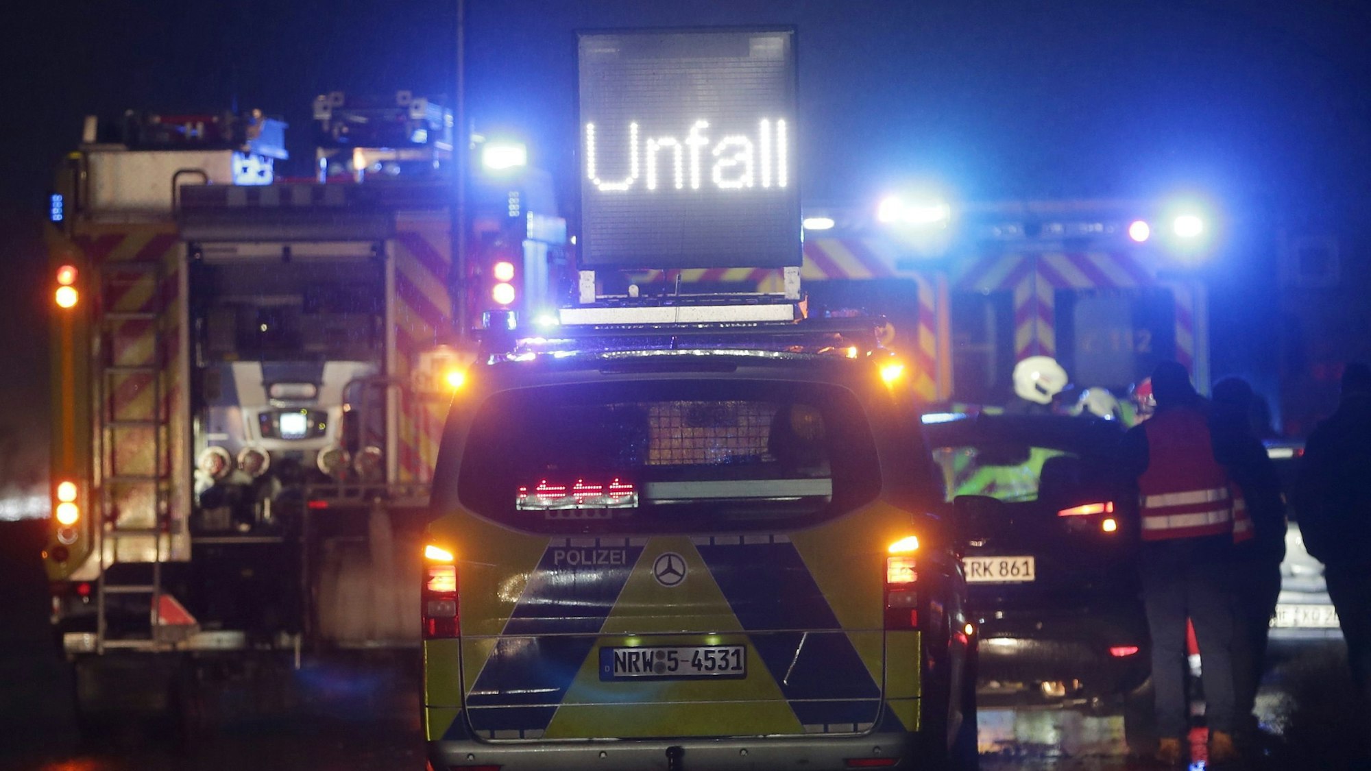 Polizei- und Feuerwehrfahrzeuge mit Blaulicht sichern eine Unfallstelle auf der Autobahn 3.