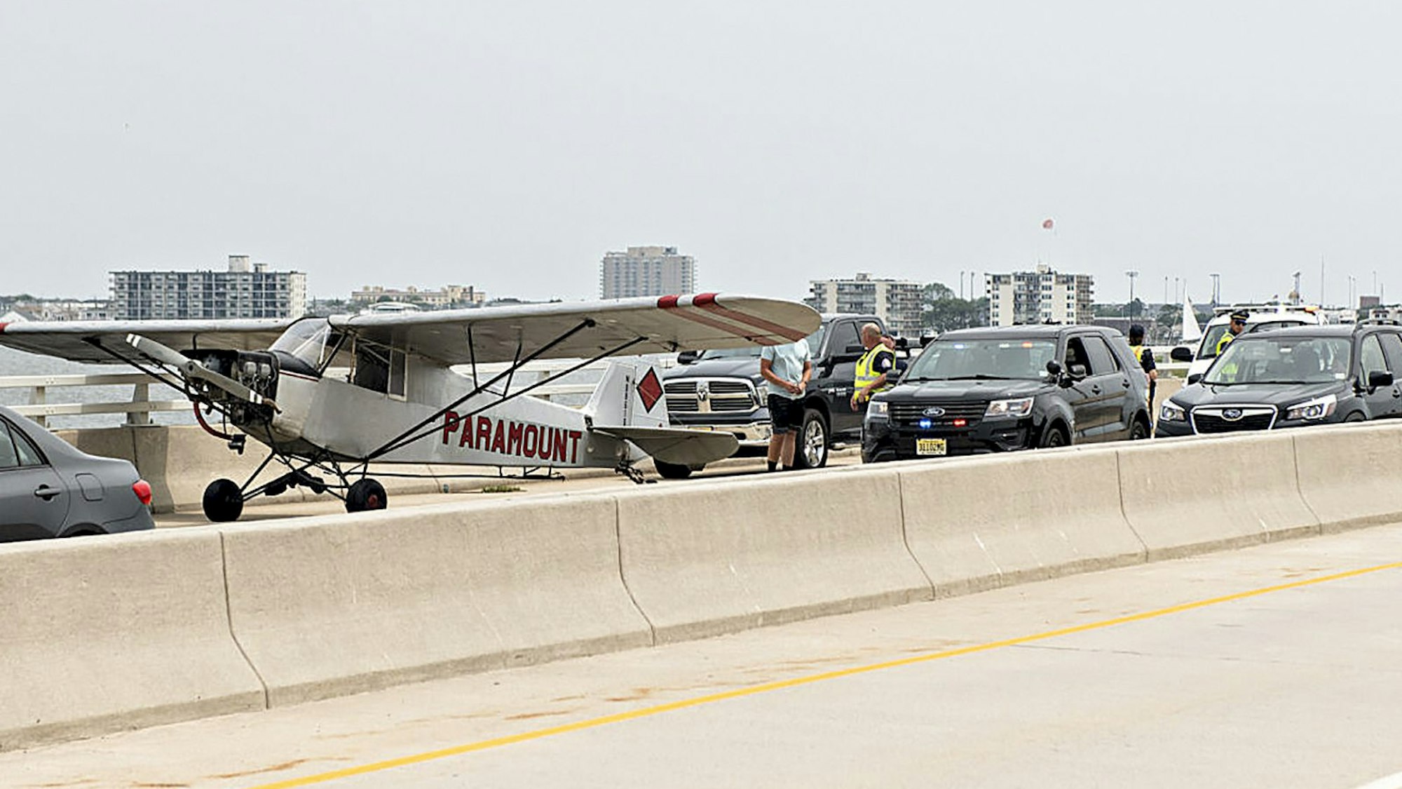Rettungskräfte sprechen mit Landon Lucas (18) einem Piloten, der für Paramount Air Service fliegt, nachdem er auf einer Autobahnbrücke in Ocean City notgelandet ist.