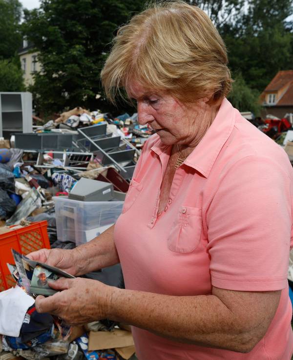 Frau in Köln vor Müllberg nach Hochwasser.