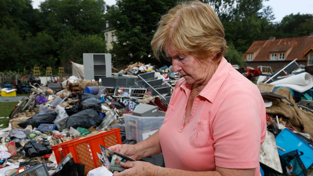 Frau in Köln vor Müllberg nach Hochwasser.