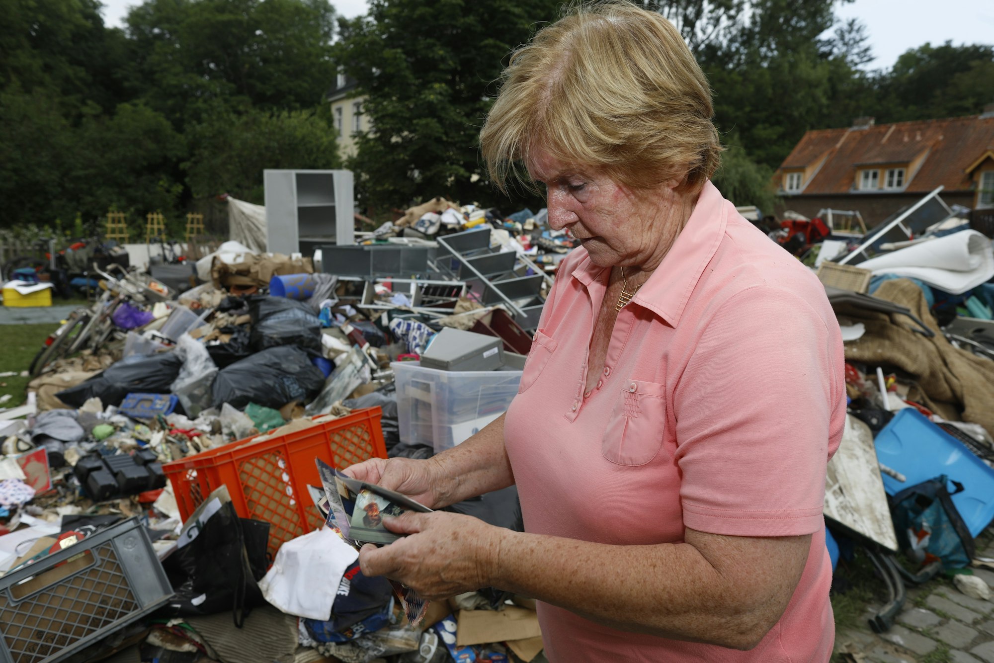Frau in Köln vor Müllberg nach Hochwasser.
