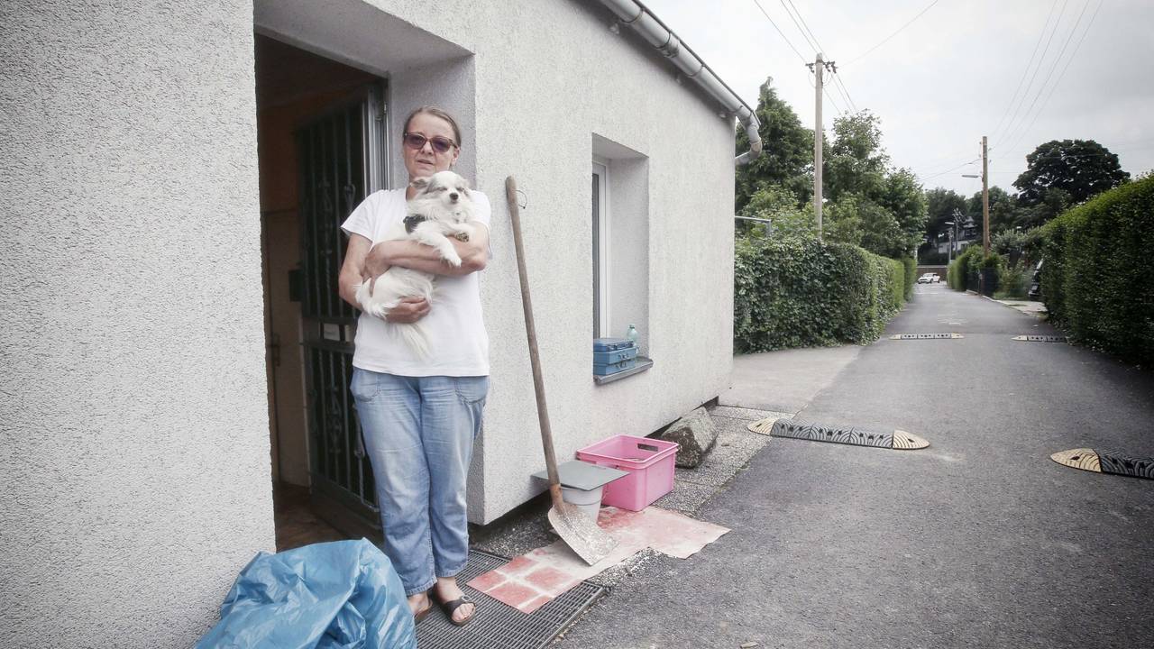 Eine Frau steht mit ihrem Hund vor ihrem Haus, das beim Hochwasser in Düsseldorf beschädigt wurde.