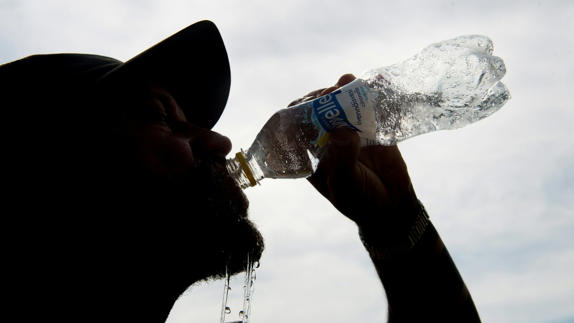 Auf unseren Symbolfoto ist ein Mann mit Mütze zu sehen, der aus einer Flasche Wasser trinkt.