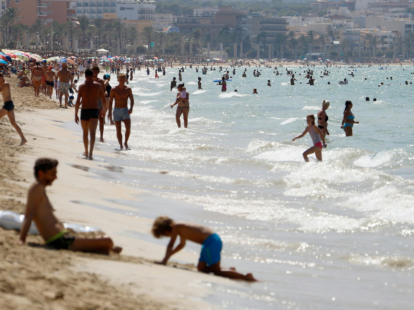 Menschen sonnen sich und schwimmen am Strand von Arenal auf Mallorca.