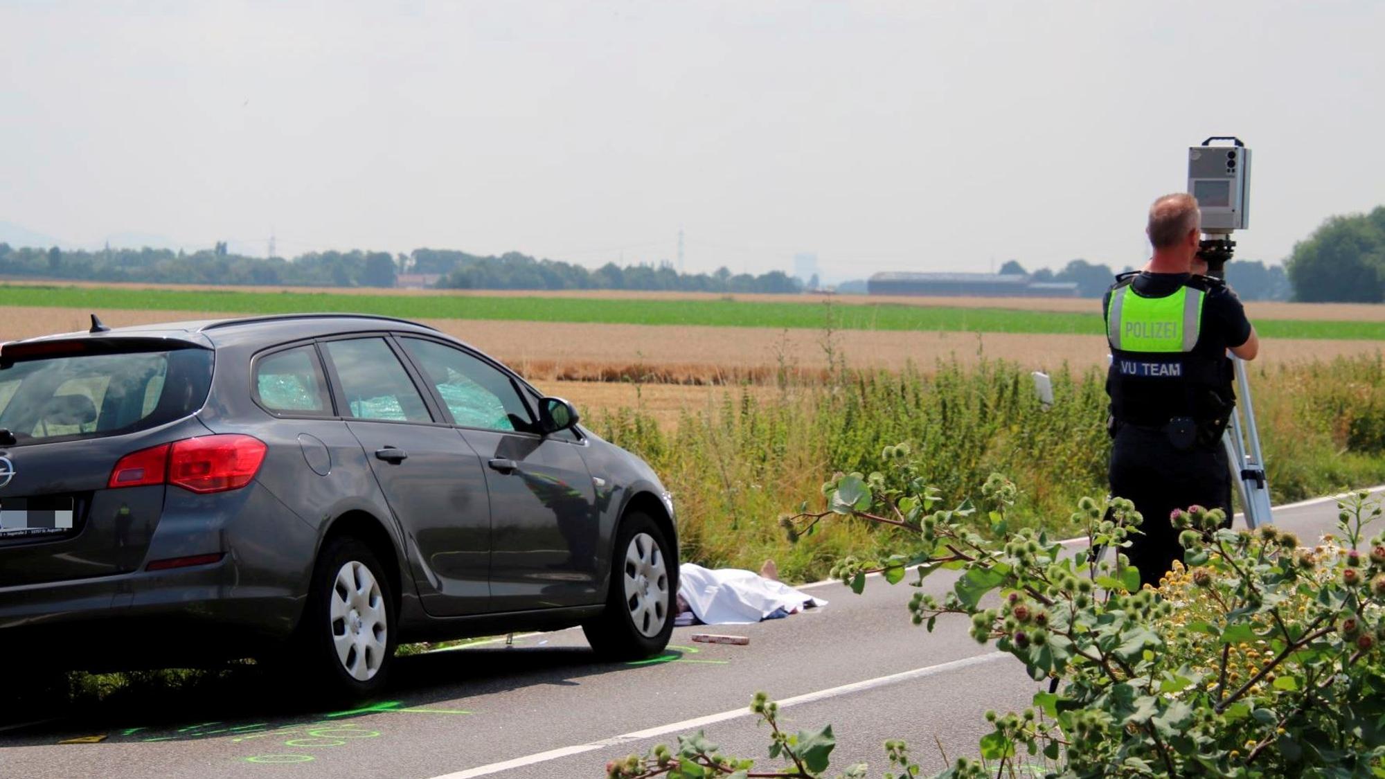 Ein Auto steht auf der Fahrbahn, davor liegt ein abgedeckter Körper.