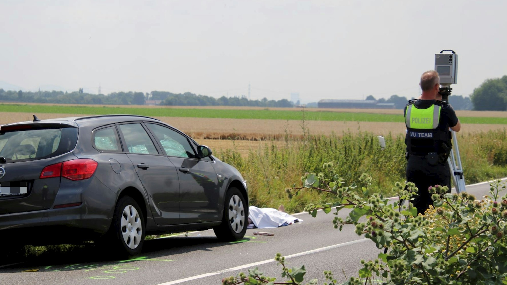 Ein Auto steht auf der Fahrbahn, davor liegt ein abgedeckter Körper.