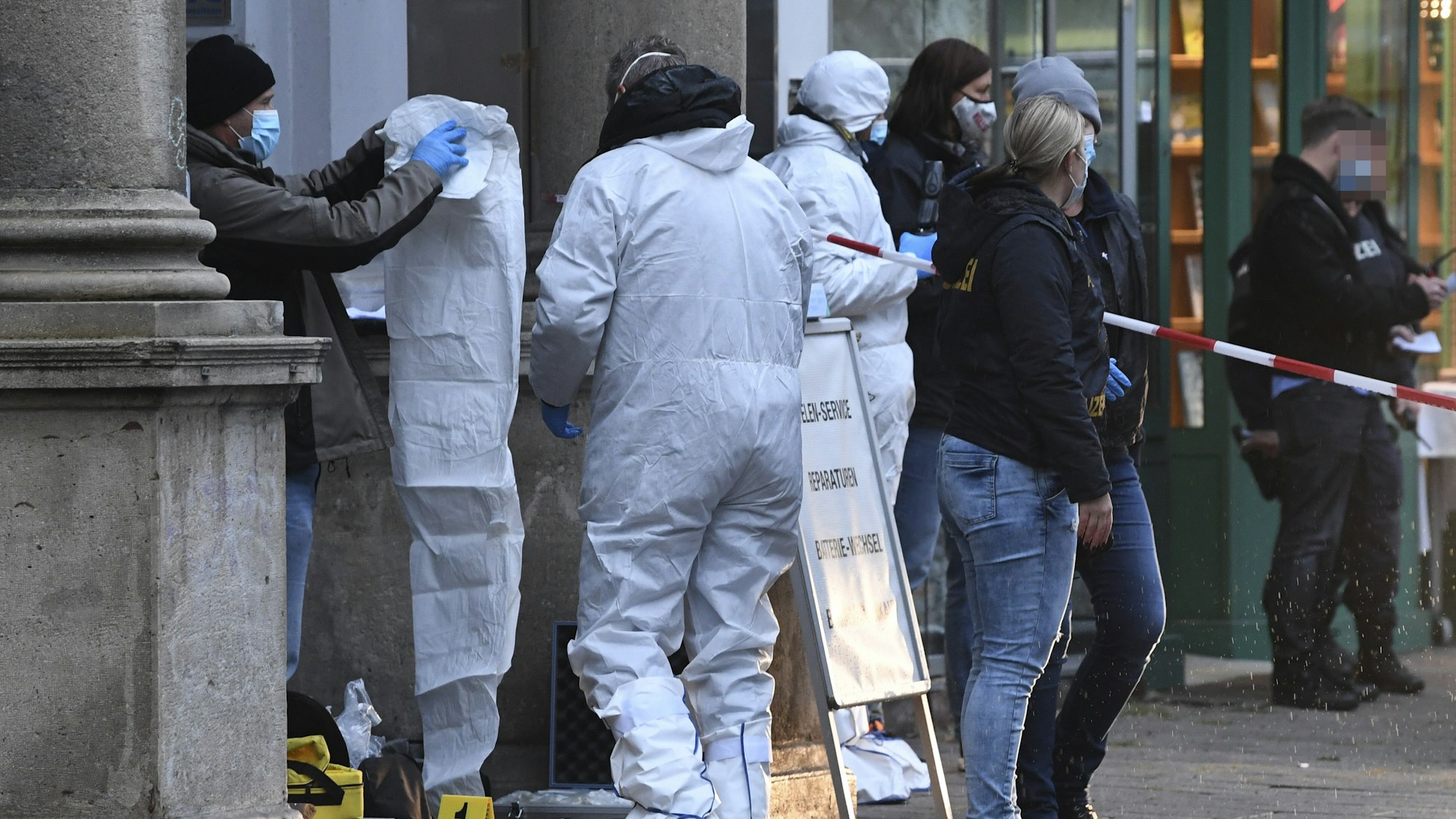 Polizisten und Beamte der Spurensicherung in Overalls ermitteln an einem Juweliergeschäft.