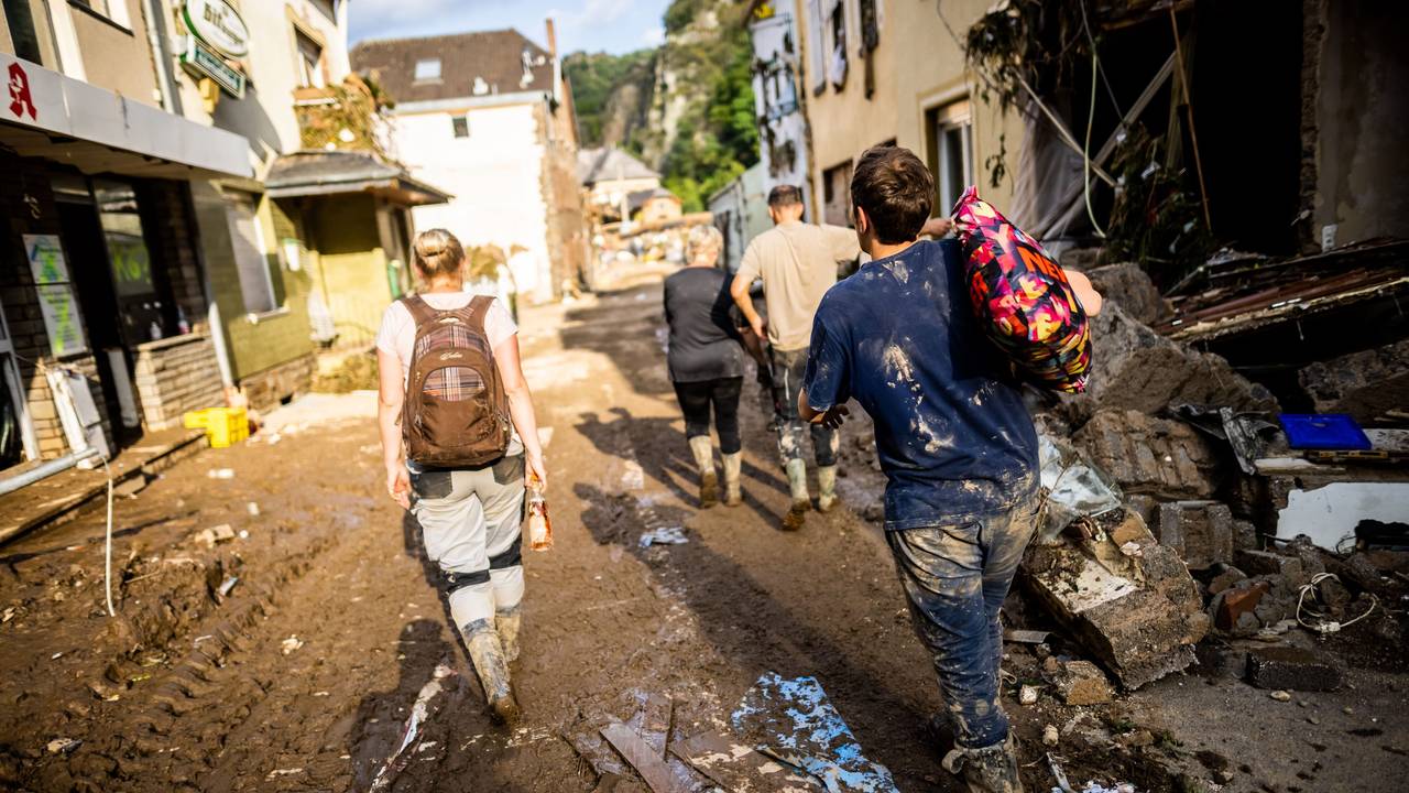 Mit Schlamm verschmierte Helfer und Helferinnen gehen durch Altenahr nach Hause.
