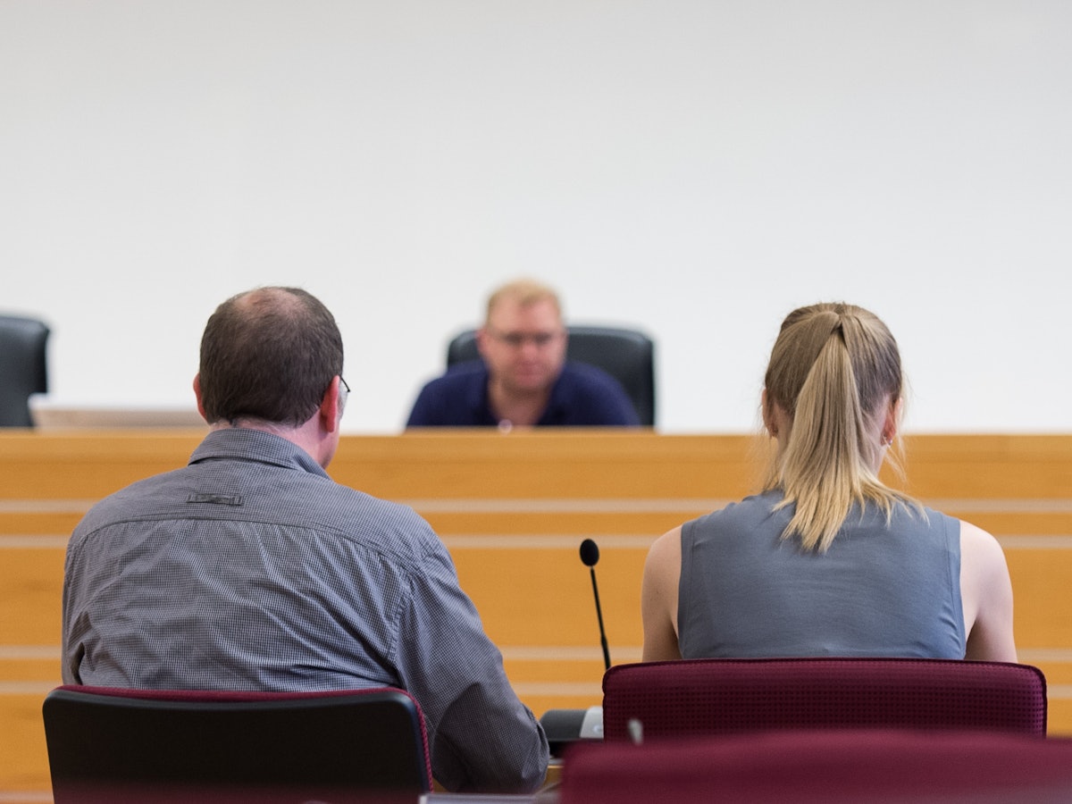 Ein Mann und eine Frau sitzen in einem Gerichtssaal vorm Richter.