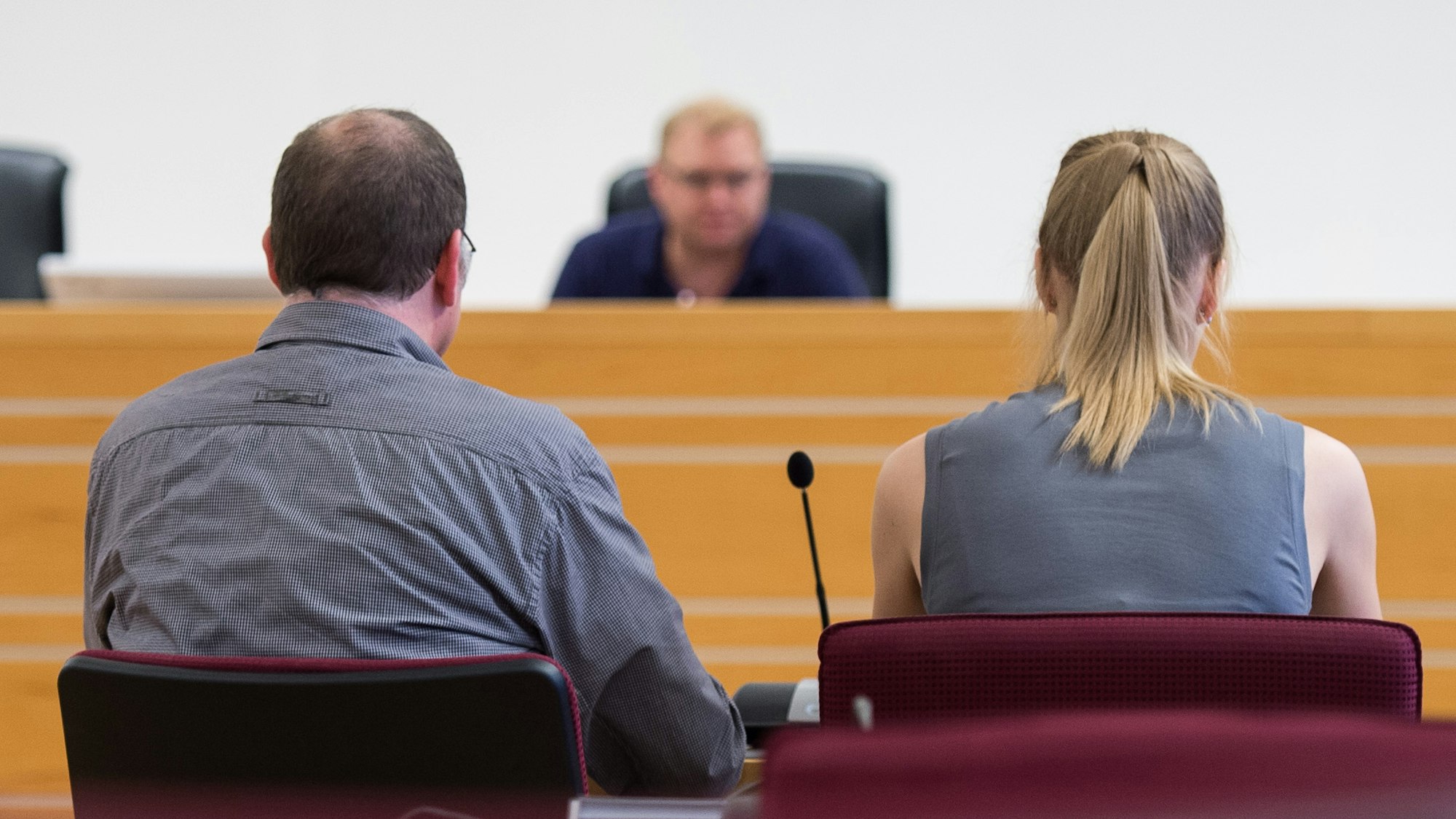 Ein Mann und eine Frau sitzen in einem Gerichtssaal vorm Richter.