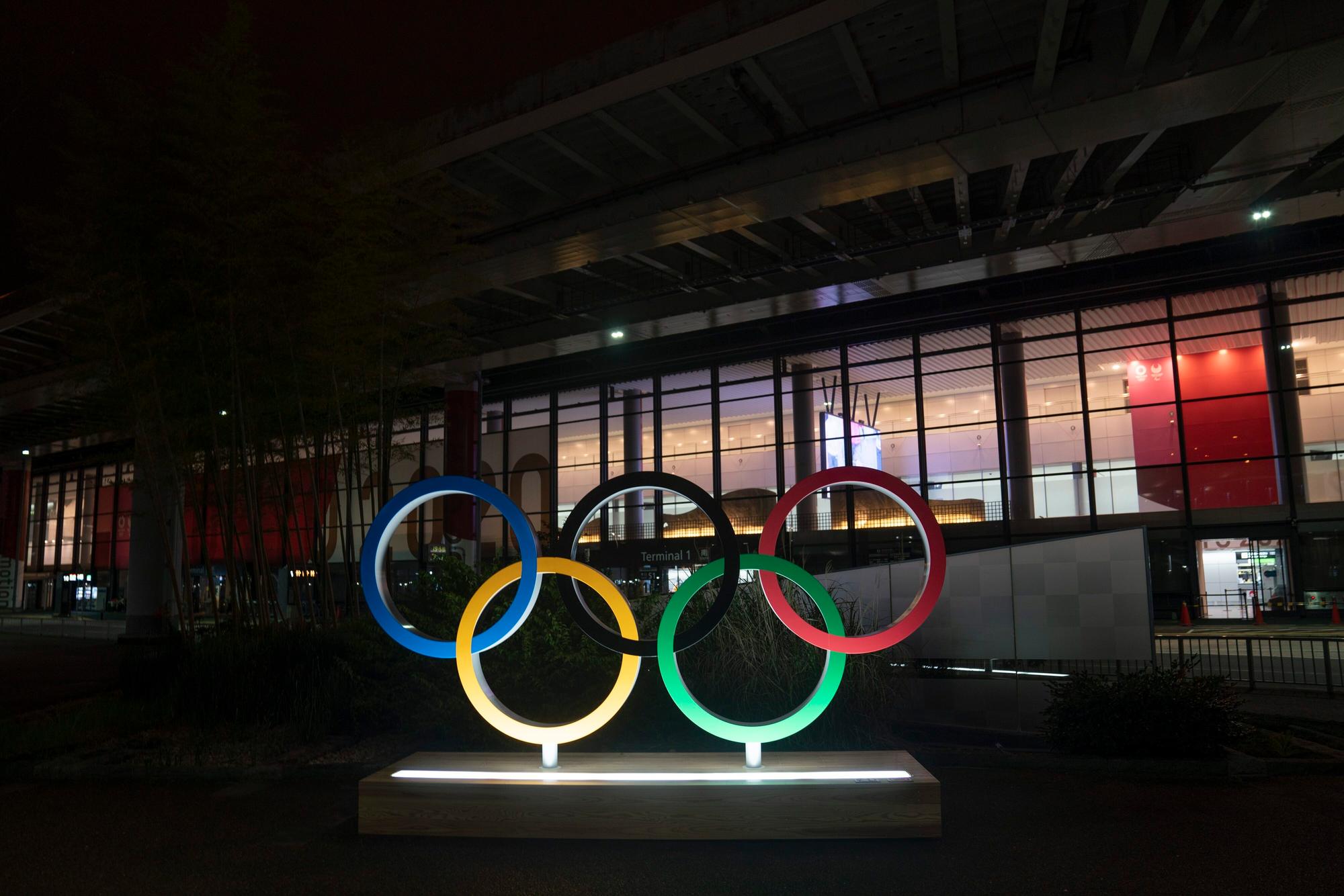 Die Olympischen Ringe werden im Dunkel vor dem Narita International Airport angeleuchtet.