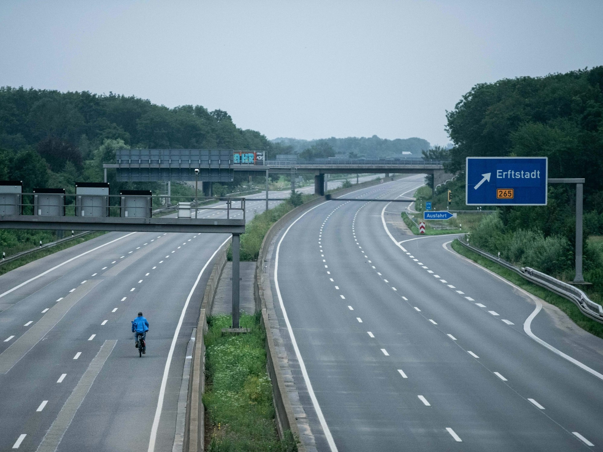 Ein Fahrradfahrer fährt über die gesperrte Autobahn A1 nahe Blessem in Erftstadt.