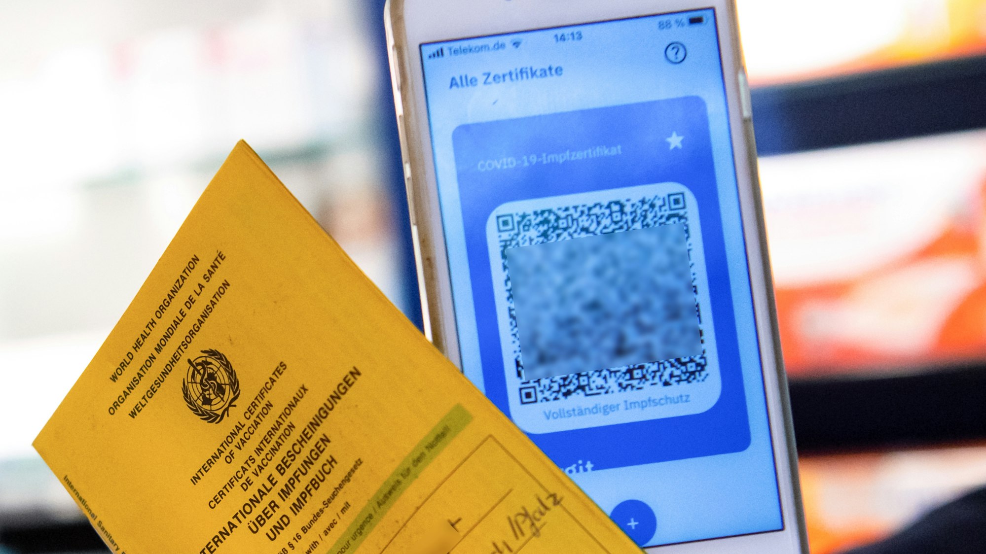 Ein Apotheker hält einen Impfpass und einen digitalen Impfnachweis in den Händen. Die Ausstellung der digitalen Impfpässe wurde jetzt erstmal gestoppt.