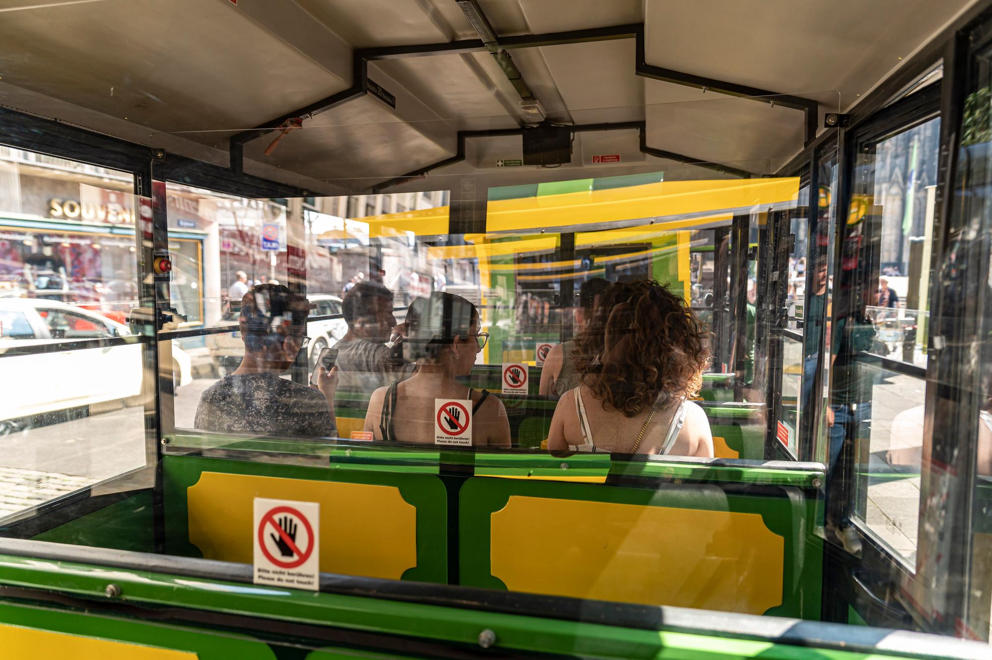 Ein Bimmelbahn fährt mit Passagieren durch Köln.