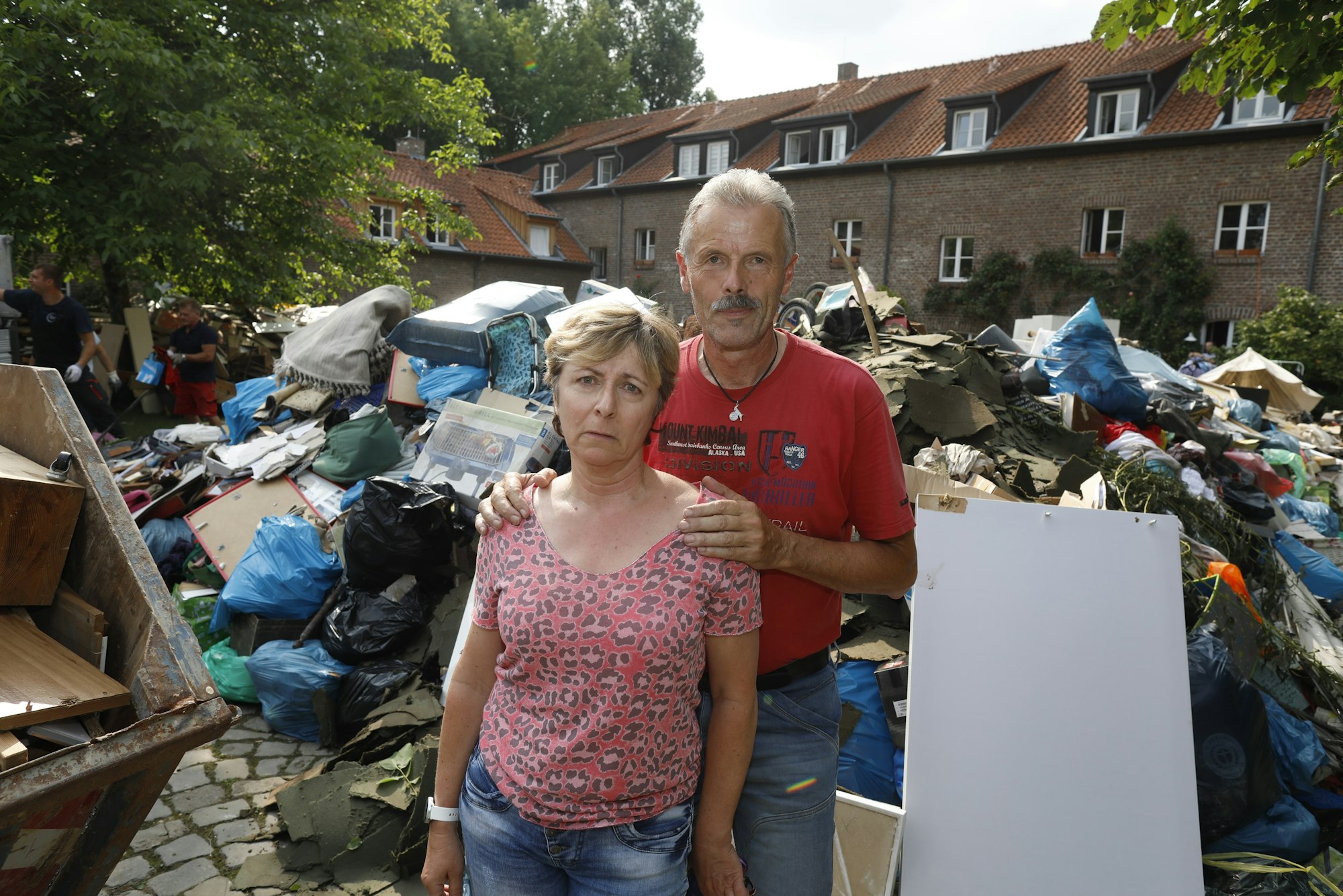 Iris und Rolf Friebel stehen in Hahn vor einem Müllberg aus Dingen, die beim Hochwasser zerstört wurden.