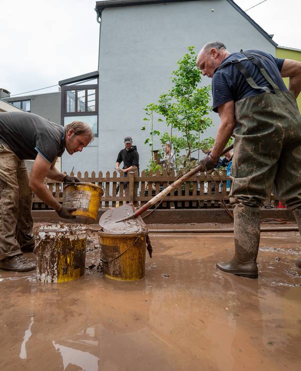 Mit Eimern entsorgen Anwohner die Schlammmassen nach dem Hochwasser der Kyll.