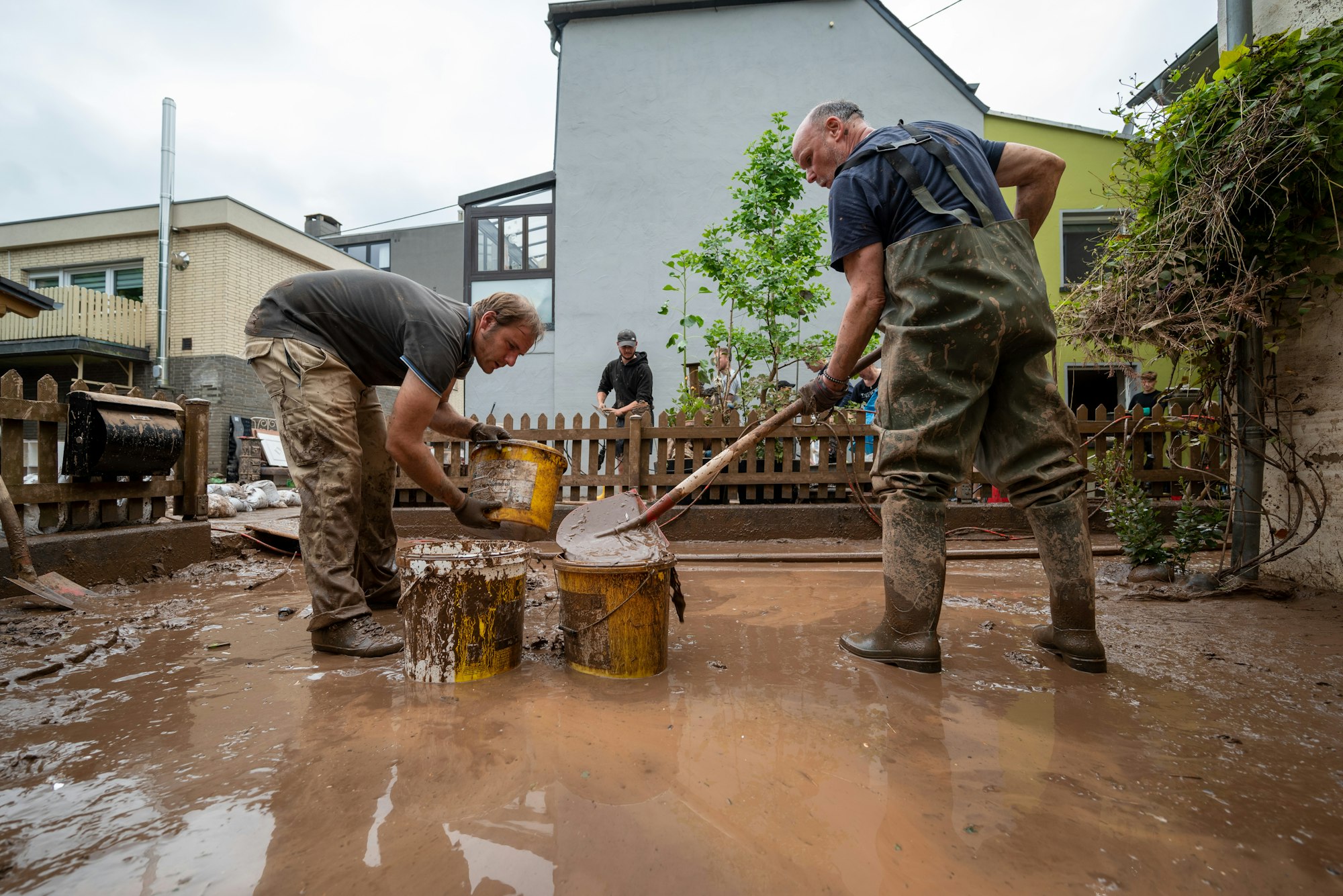 Mit Eimern entsorgen Anwohner die Schlammmassen nach dem Hochwasser der Kyll.