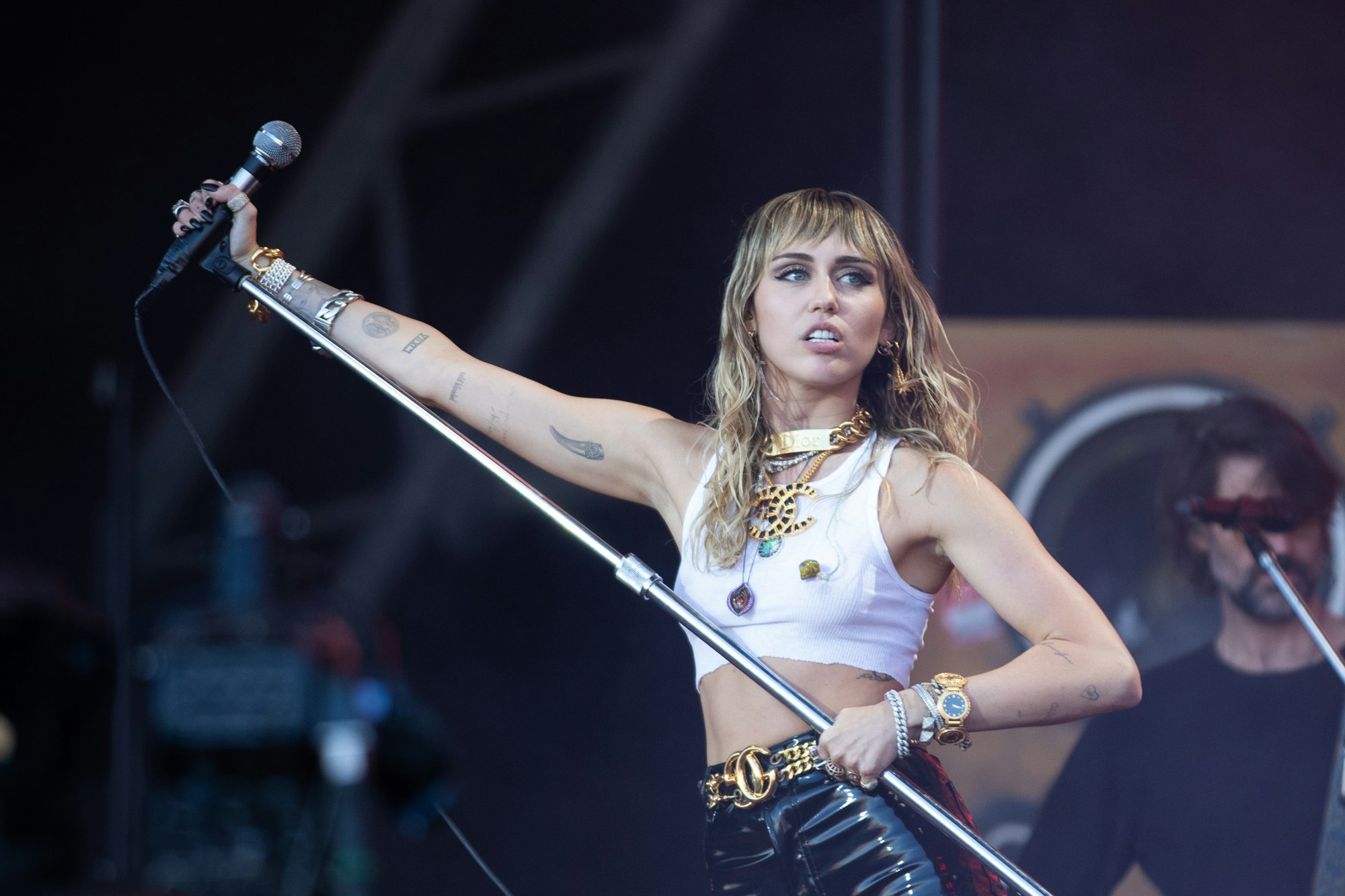 Miley Cyrus steht mit Mikrofonständer in der Hand bei einem Festival auf der Bühne.
