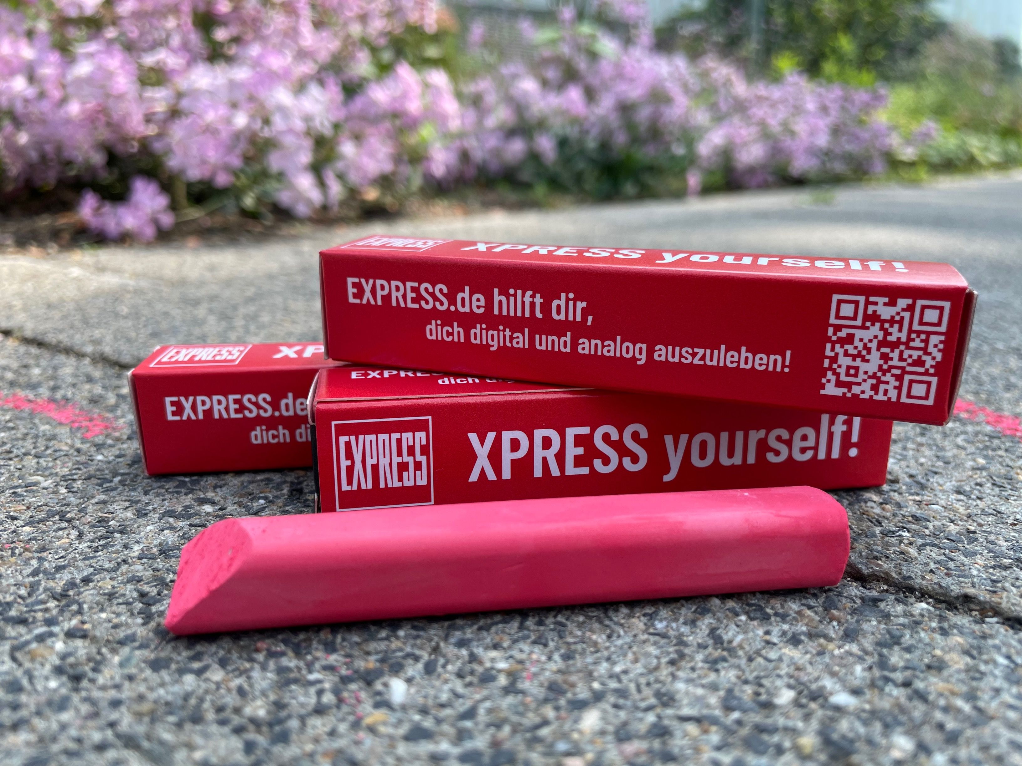 Kreide von EXPRESS.de liegt auf dem Bürgersteig vor dem Kölner Neven DuMont Haus.