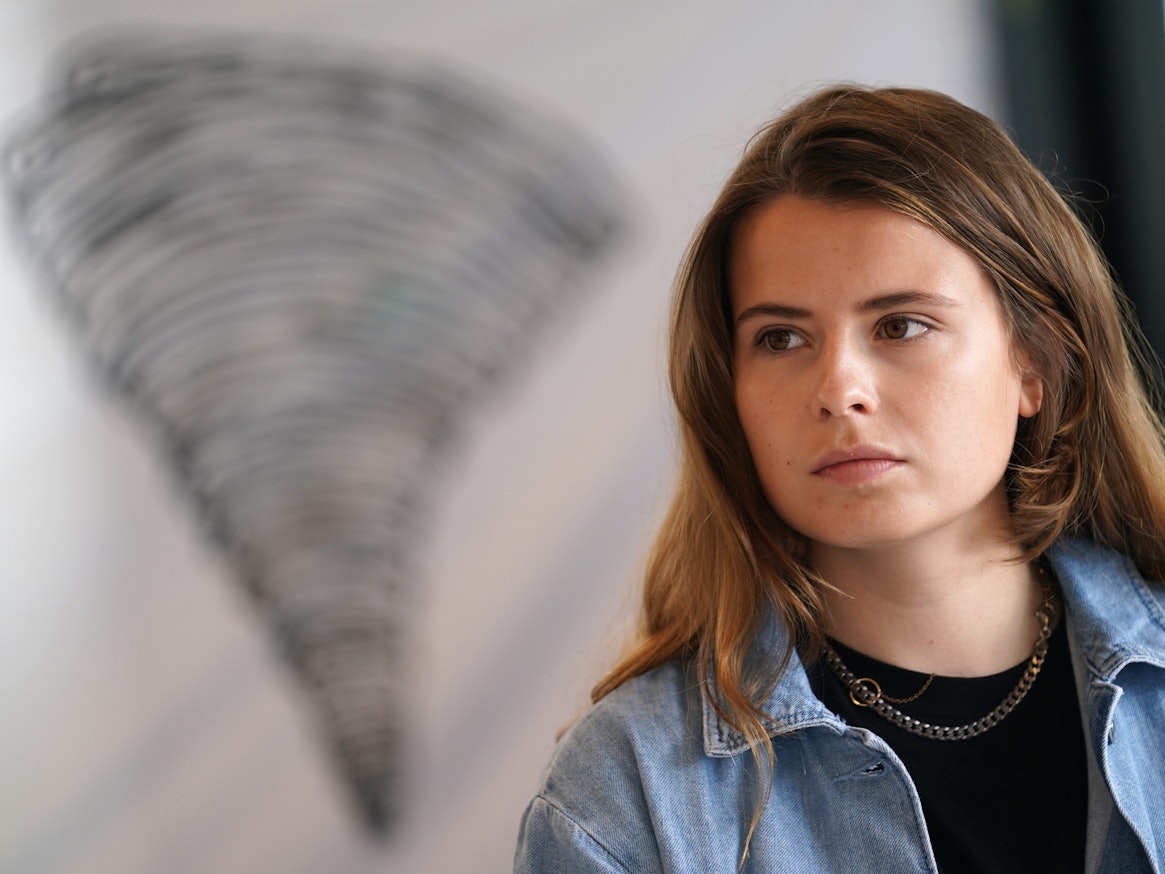 Klima-Aktivistin Luisa Neubauer sitzt während einer Pressekonferenz des Bündnisses Fridays for Future am 23.07.2021 vor dem Symbol eines Tornados.