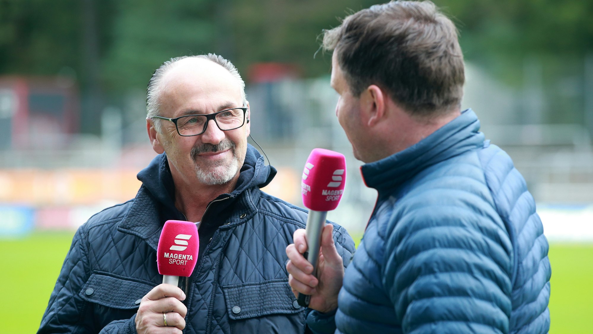 Jürgen Kohler hält bei einer TV-Schalte das Mikrofon von MagentaSport in der Hand.
