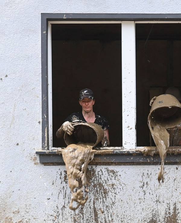 Unmittelbar nach der Flut kippen Helfer Schlamm aus Eimern in einem Haus in Dernau (Ahrtal)