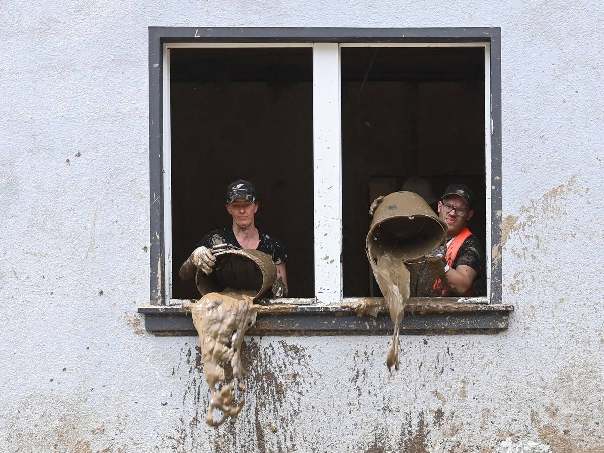 Unmittelbar nach der Flut kippen Helfer Schlamm aus Eimern in einem Haus in Dernau (Ahrtal)