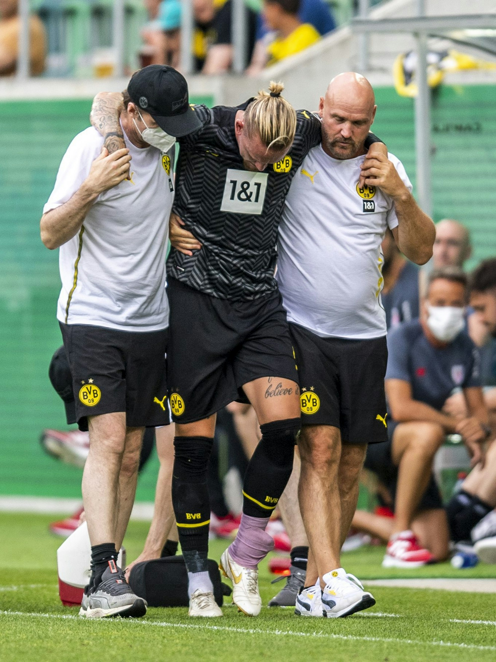 Marius Wolf verlässt gestützt von Betreuern und mit bandagiertem Knöchel den Platz.