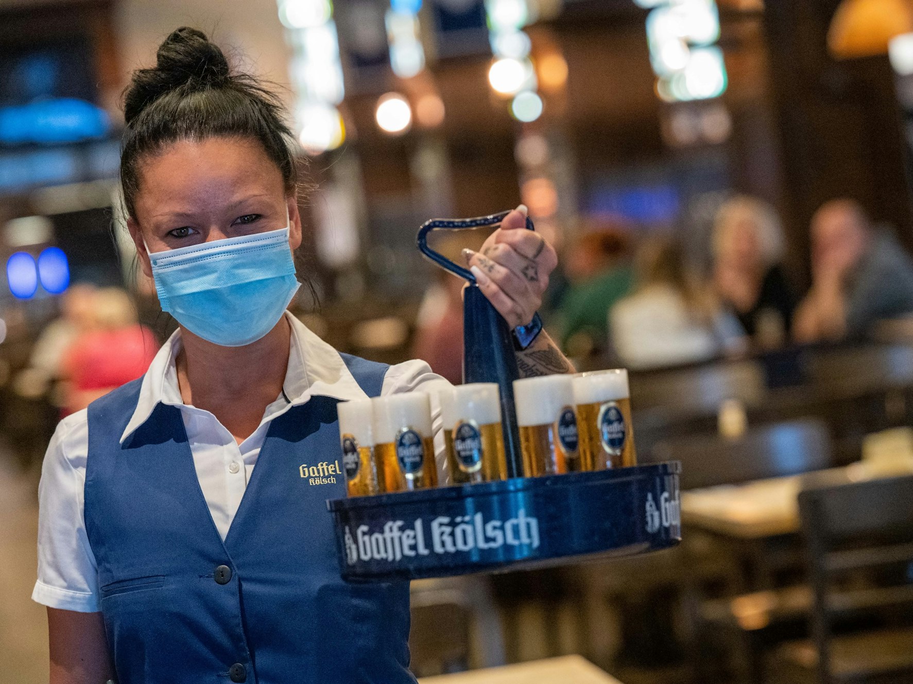 Eine Bedienung mit Kölschkranz und Mund-Nase-Maske im Brauhaus Gaffel am Dom.