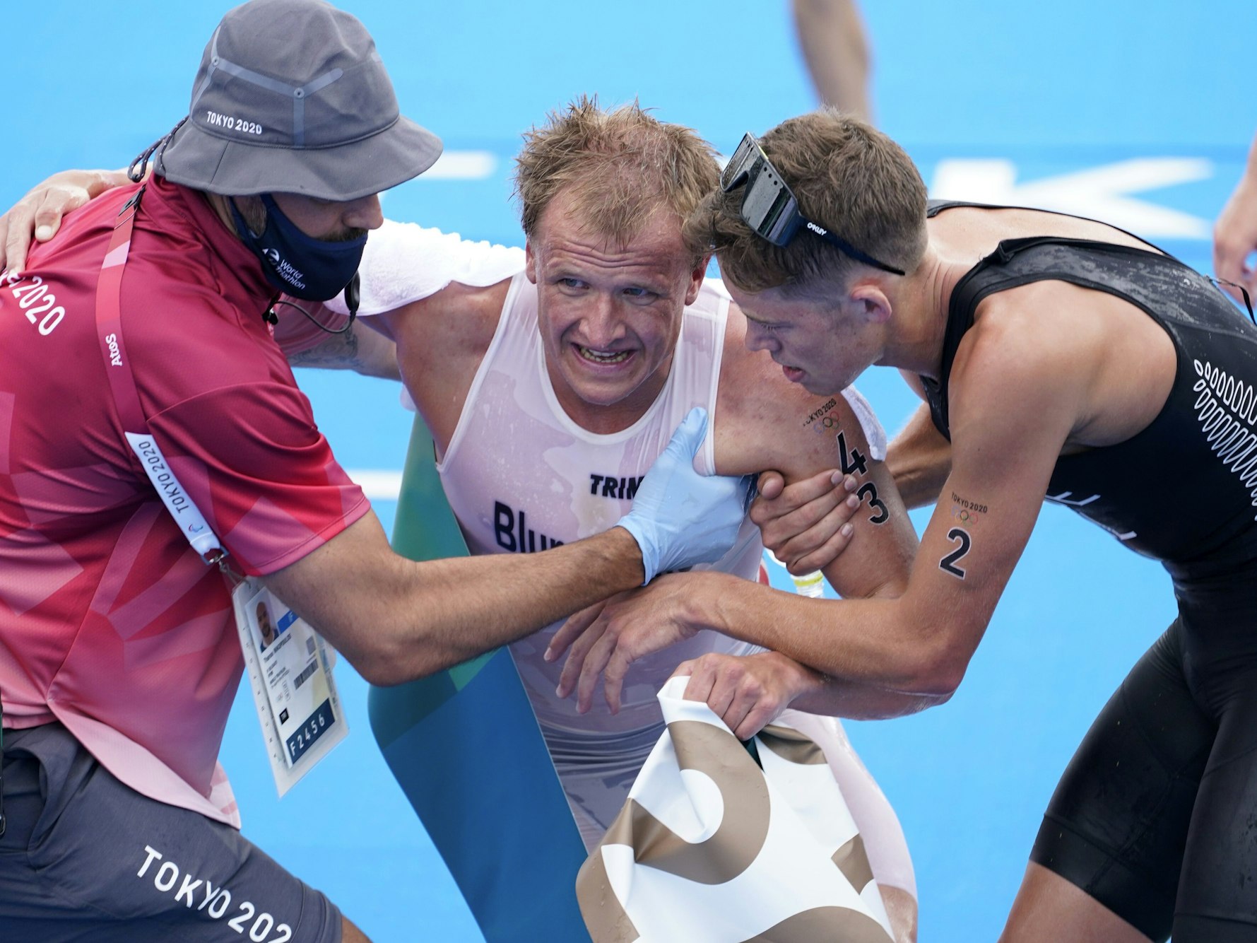 Kristian Blummenfelt wird von einem Betreuer und dem Drittplatzierten Hayden Wilde aufgeholfen.