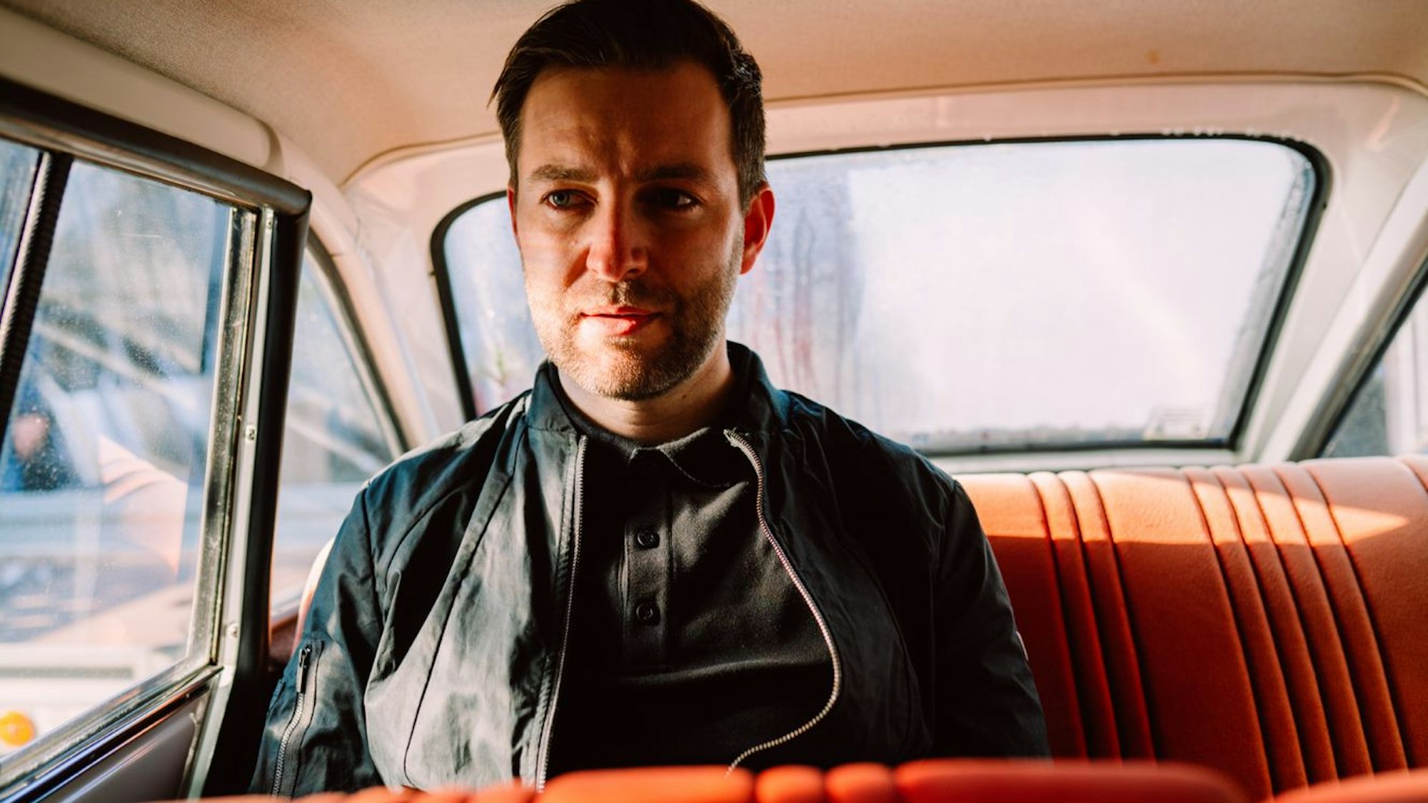 Sänger Josh. sitzt auf dem Rücksitz eines Autos und schaut durch das Fenster