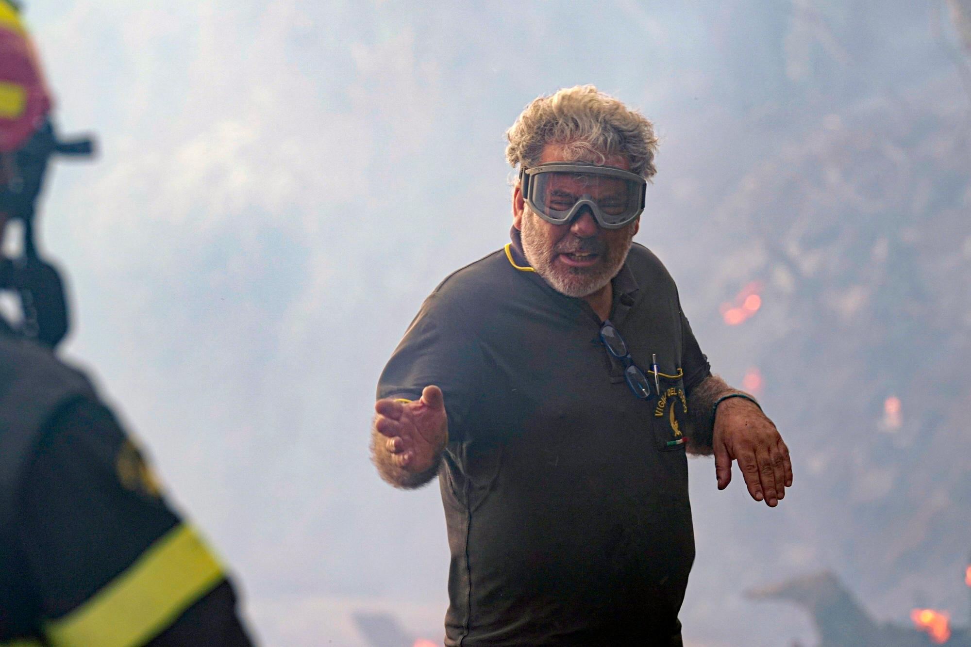 Ein Feuerwehrmann spricht bei Löscharbeiten in der Nähe von Oristano mit seinem Kollegen.