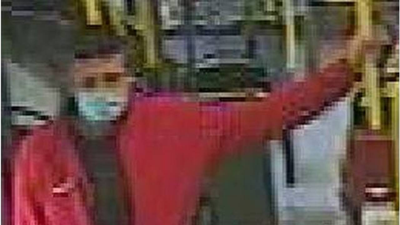 Mann in roter Jacke lehnt an Geländer in einem Bus in Köln.