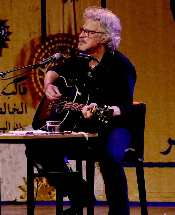 Wolfgang Niedecken spielt auf einer Bühne Gitarre und singt.