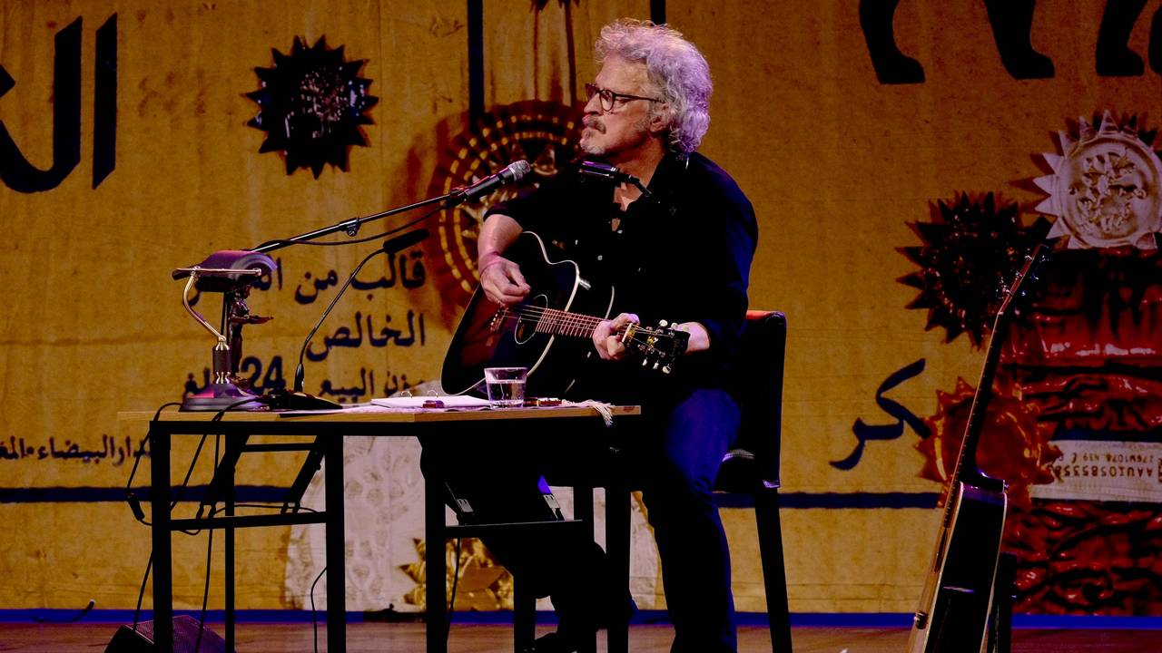 Wolfgang Niedecken spielt auf einer Bühne Gitarre und singt.