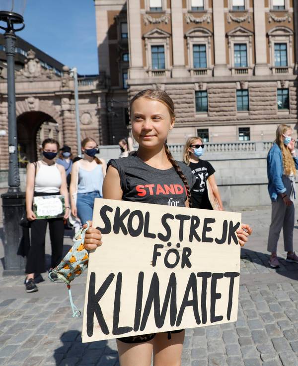 Greta Thunberg ist geimpft und hält ihr Schild mit der Aufschrift „Skolstrejk för Klimatet” in den Händen.