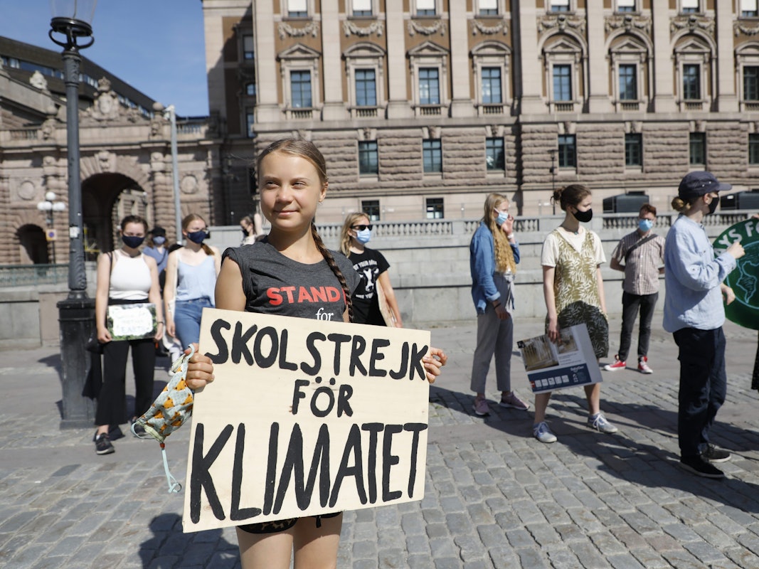 Greta Thunberg ist geimpft und hält ihr Schild mit der Aufschrift „Skolstrejk för Klimatet” in den Händen.