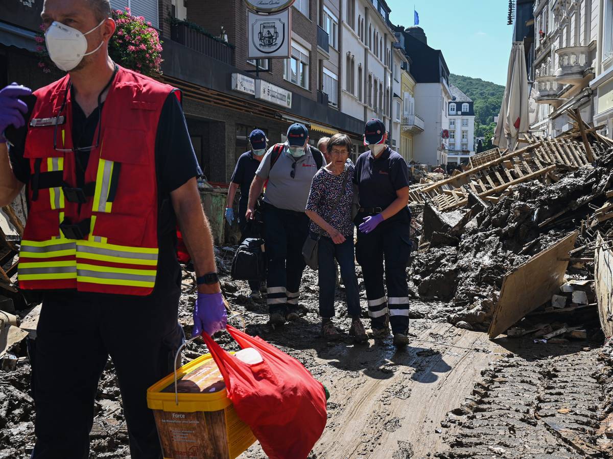 Helfer der Johanniter in Bad Neuenahr-Ahrweiler begleiten nach der Flutkatastrophe eine Seniorin aus ihrer Wohnung.