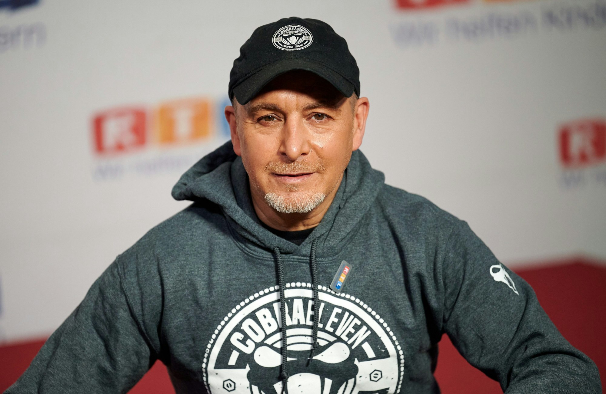 Der Schauspieler Erdogan Atalay sitzt beim 25. RTL Spendenmarathon vor einer Fotowand.