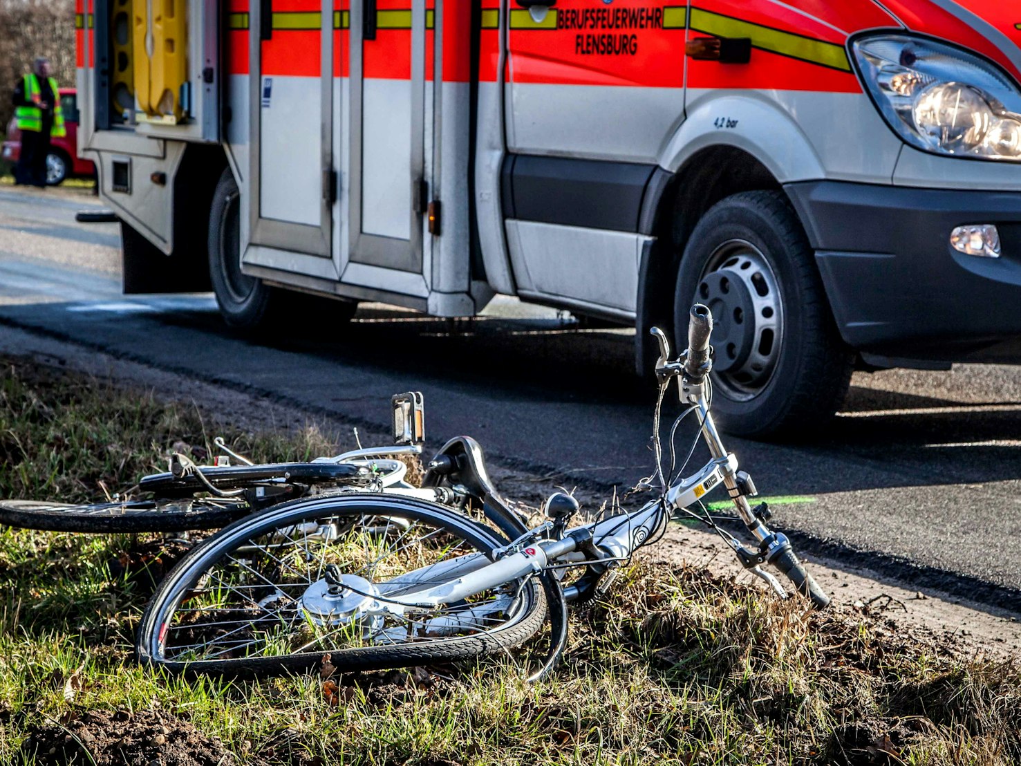 Ein zerstörtes Fahrrad liegt neben einer Straße im Gras.