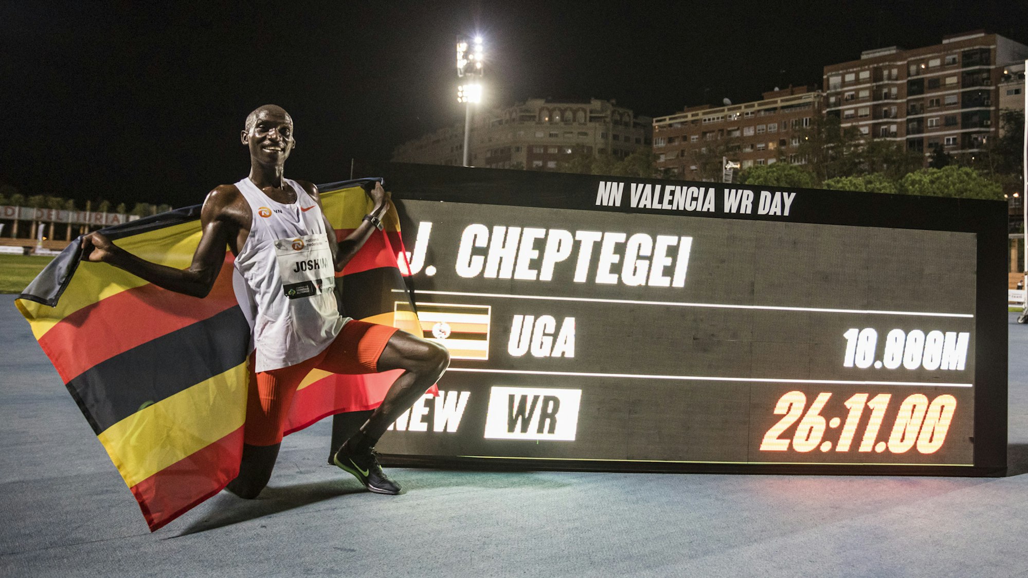 Joshua Cheptegei posiert neben einem Bildschirm mit seinem Weltrekord.