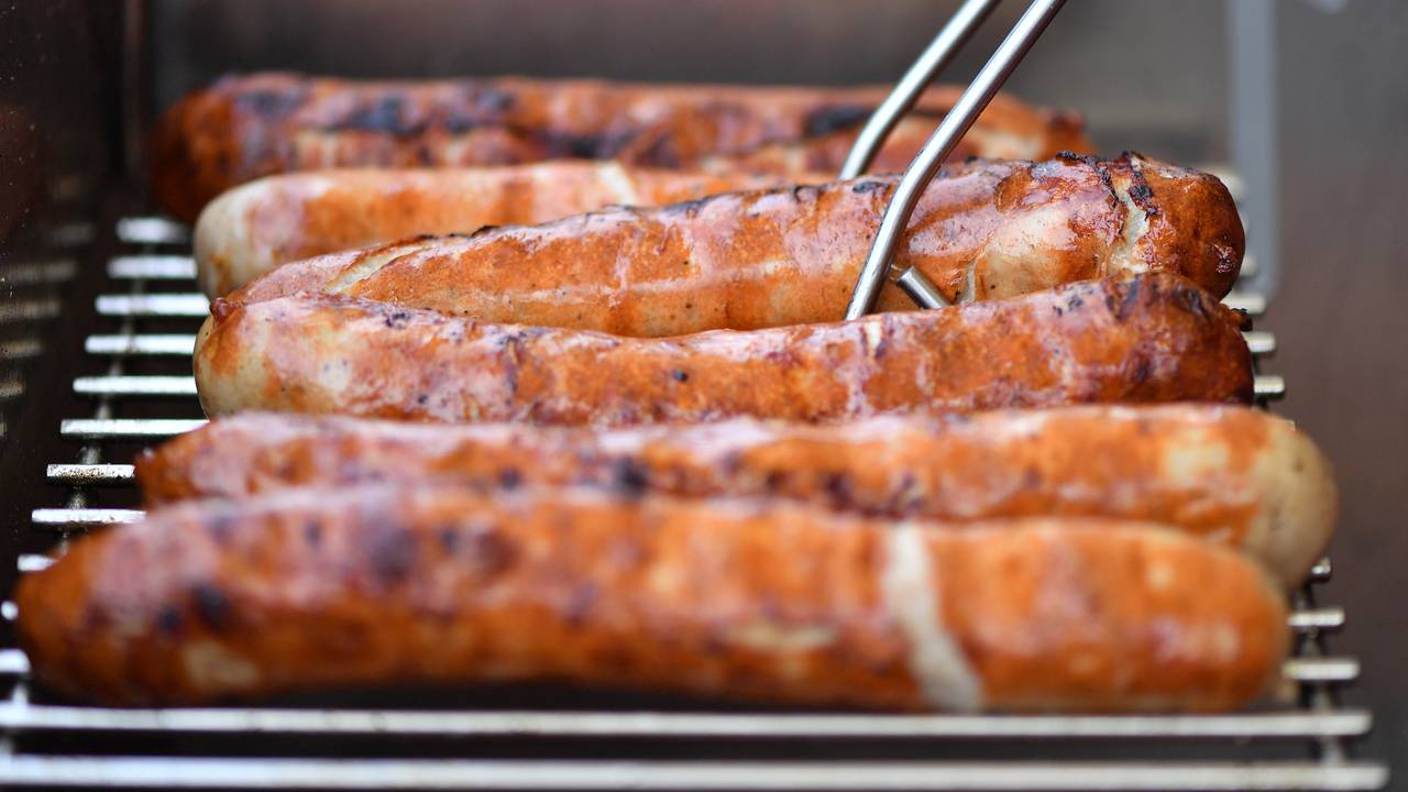 Auf einem Grill liegen sechs braun gebrutzelte Thüringer Bratwürste nebeneinander.