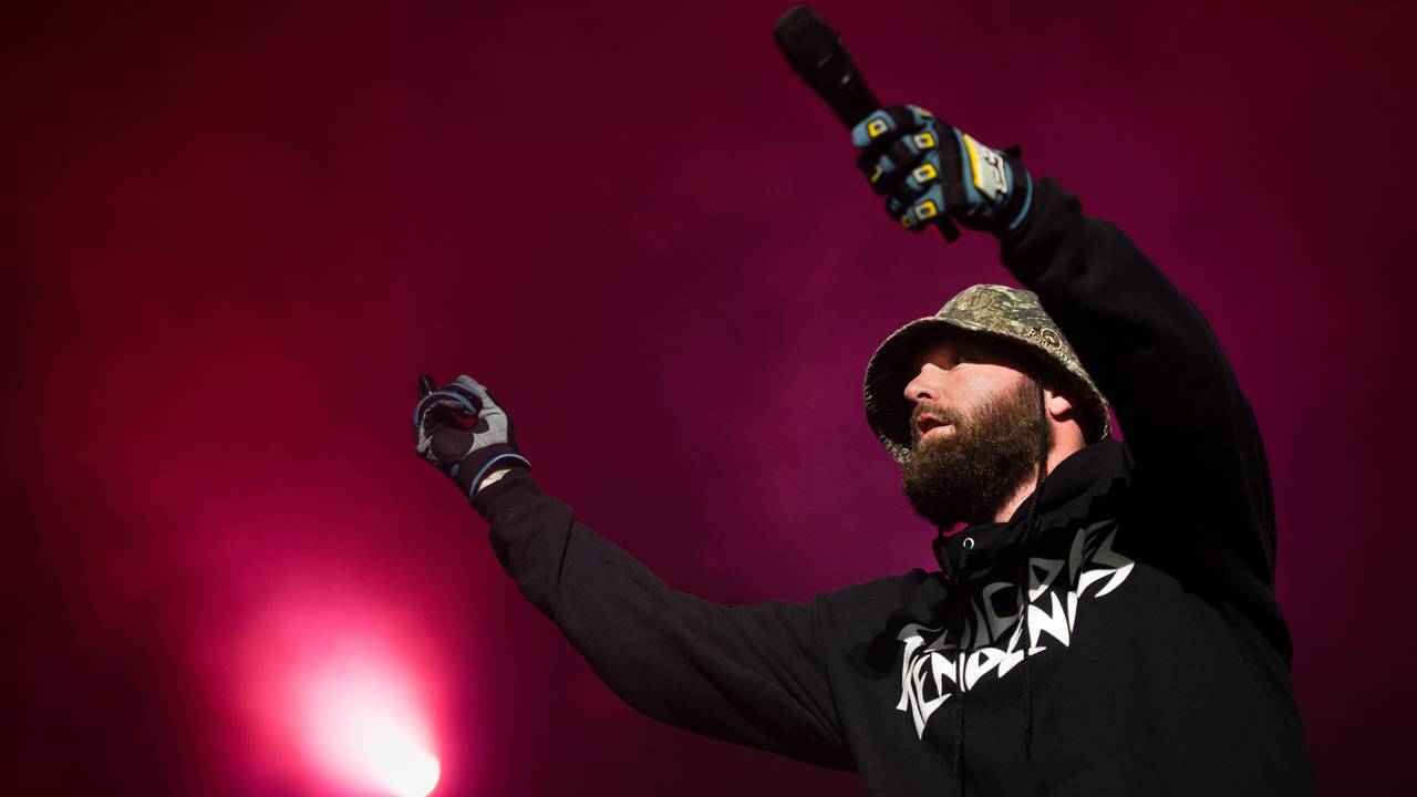 Fred Durst trägt auf der Bühne einen Anglerhut, einen dichten Bart, einen langärmeligen Kaputzen-Pulli und Handschuhe.