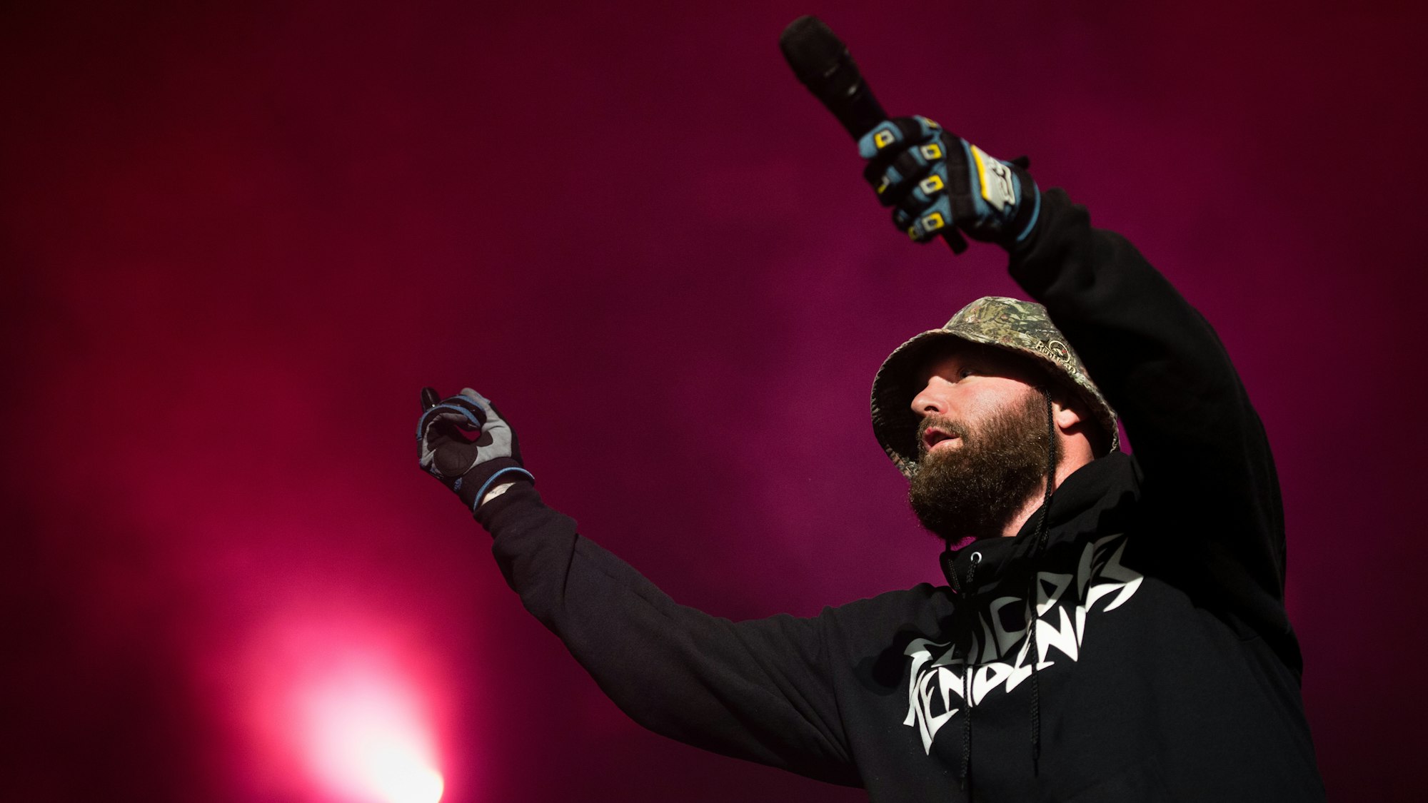 Fred Durst trägt auf der Bühne einen Anglerhut, einen dichten Bart, einen langärmeligen Kaputzen-Pulli und Handschuhe.