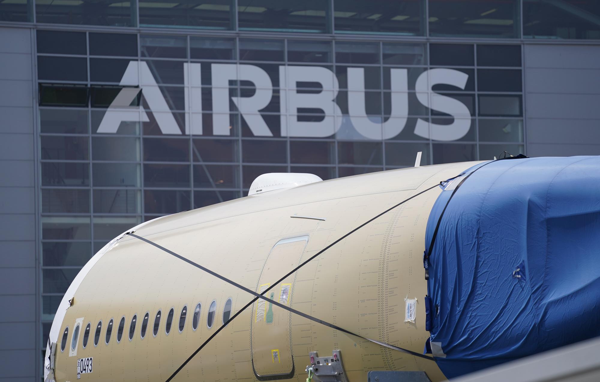 Ein Segment eines Flugzeugrumpfes eines Airbus A350 stehen vor einer Fertigungshalle auf dem Werksgelände des Flugzeugbauers Airbus.
