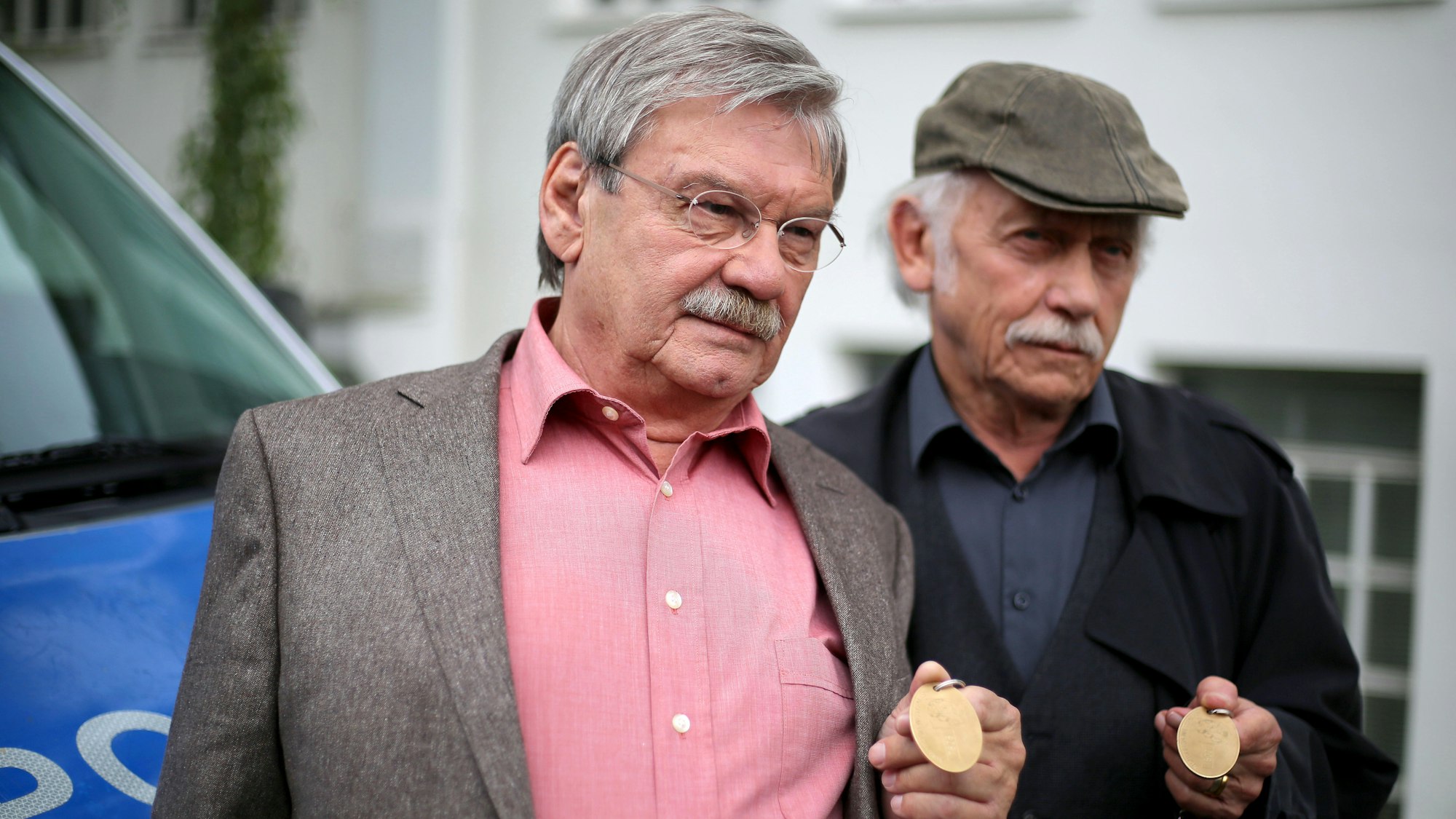 Die Schauspieler der ARD-Vorabendserie "Rentnercops" Tilo Prückner (r) als Kommissar Edwin Bremer und Wolfgang Winkler als Kommissar Günter Hoffmann stehen am 30.06.2016 in Köln (Nordrhein-Westfalen) in einer Drehpause an einem Polizeifahrzeug am Set.