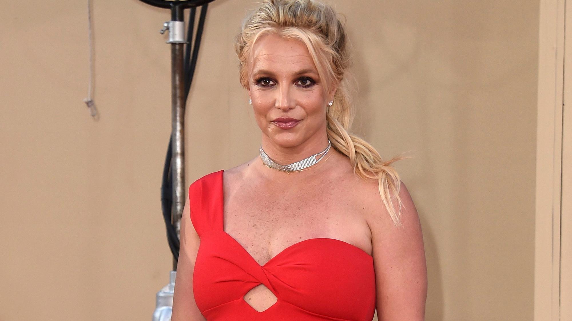 Britney Spears posiert im roten Kleid bei einer Veranstaltung.